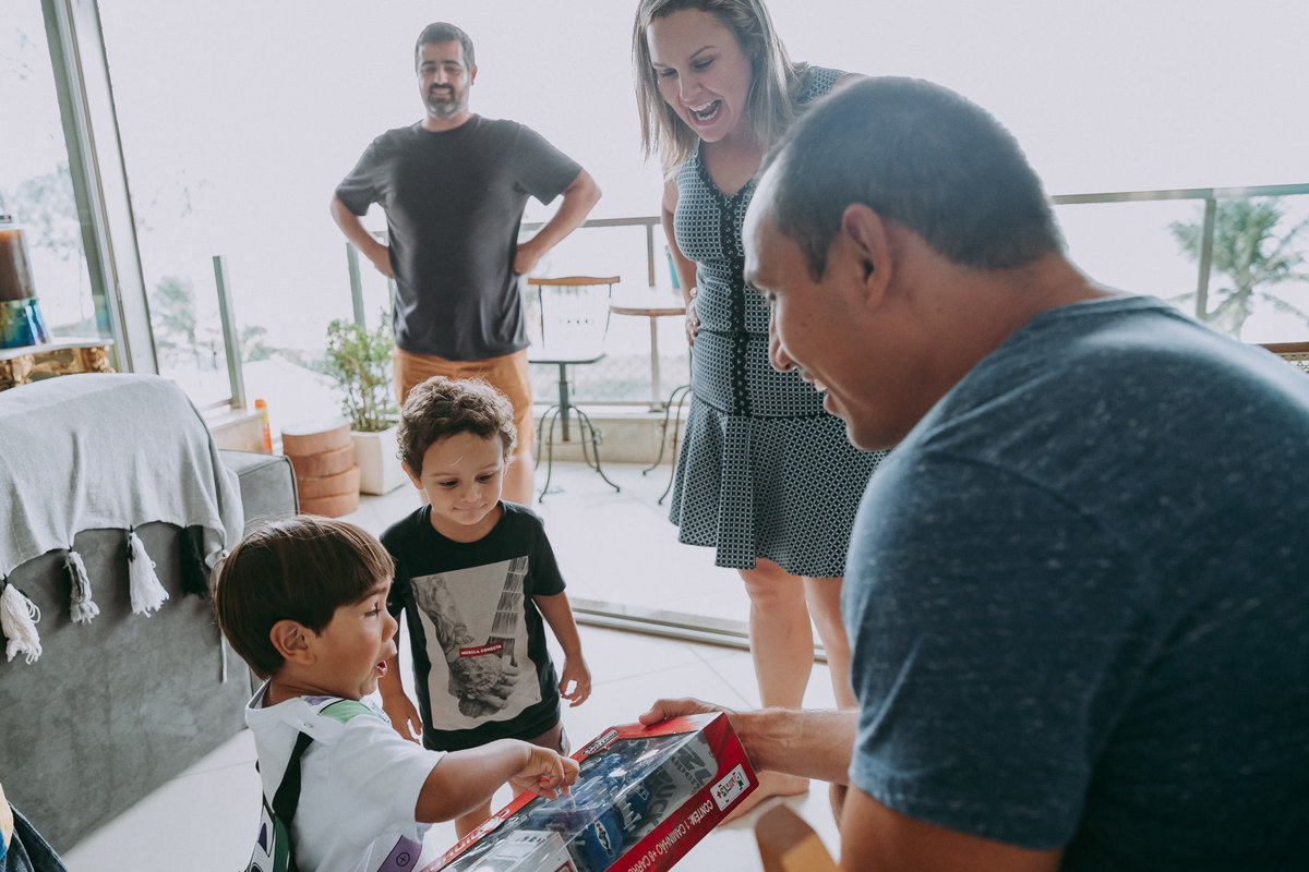 criança de 2 anos faz cara supresa ao ver que ganhou um caminhao de brinquedo