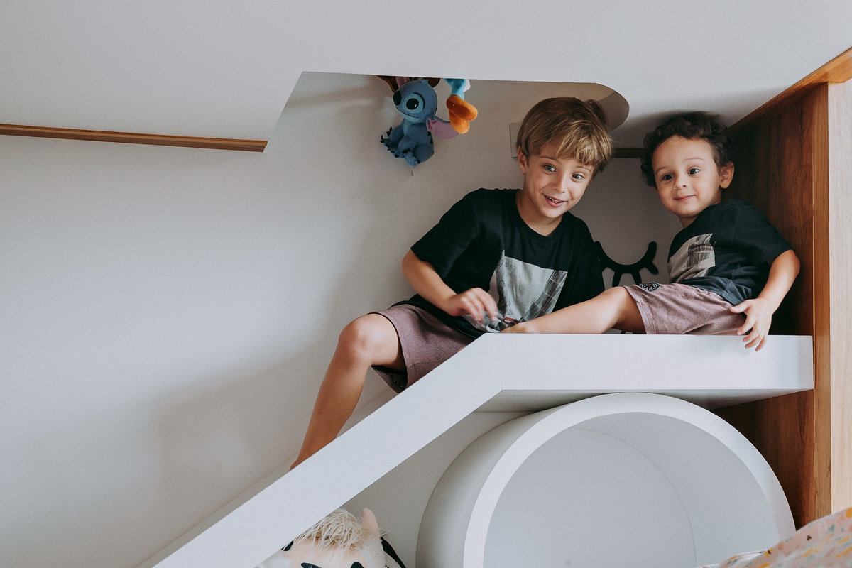 irmãos em escorrega de cama de quarto