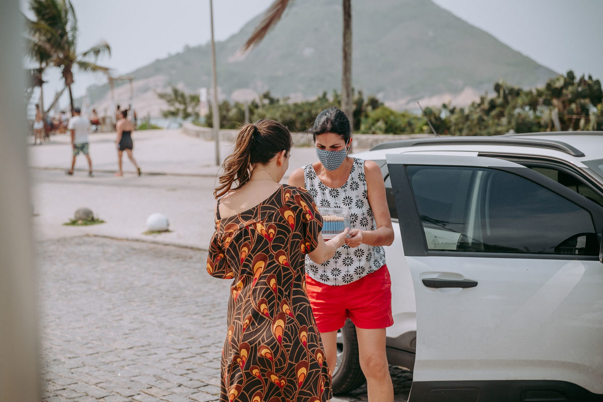 foto documental de mulher na rua pegando encomenda de outra mulher em carro branco