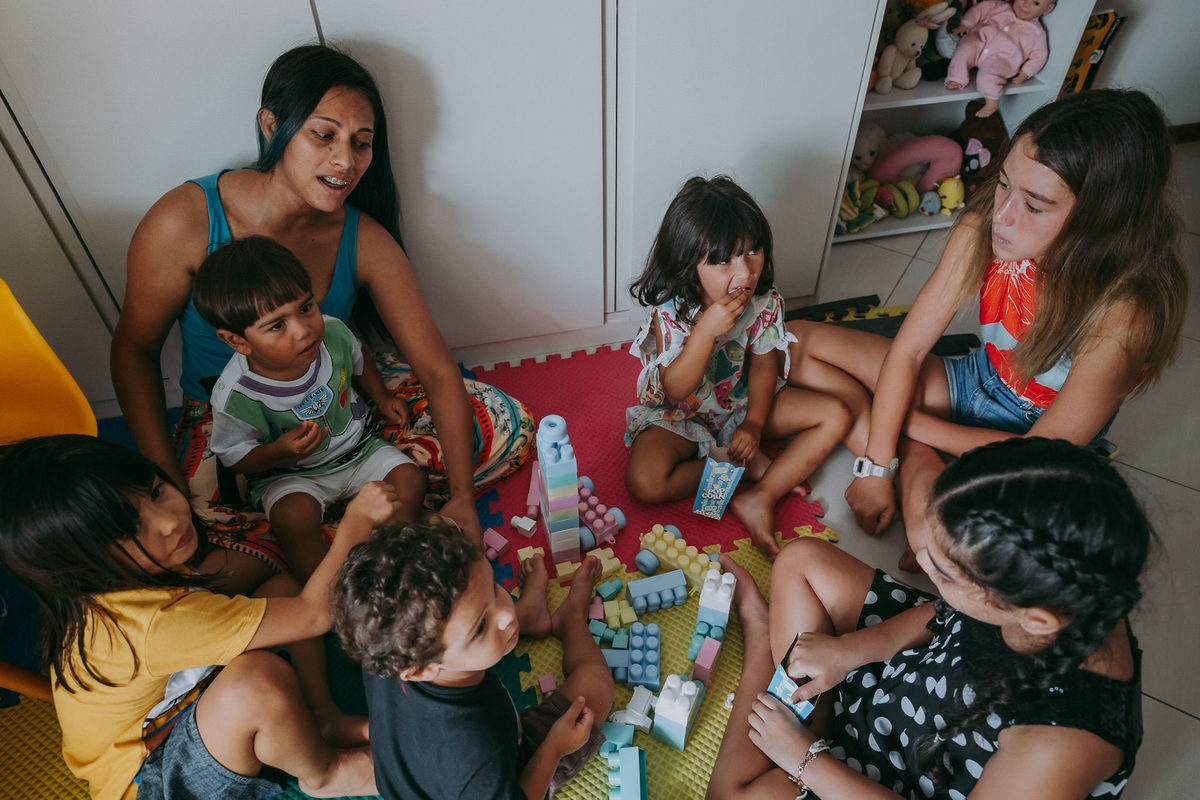 grupo de crianças sentadas no chão do quarto comendo e brincando