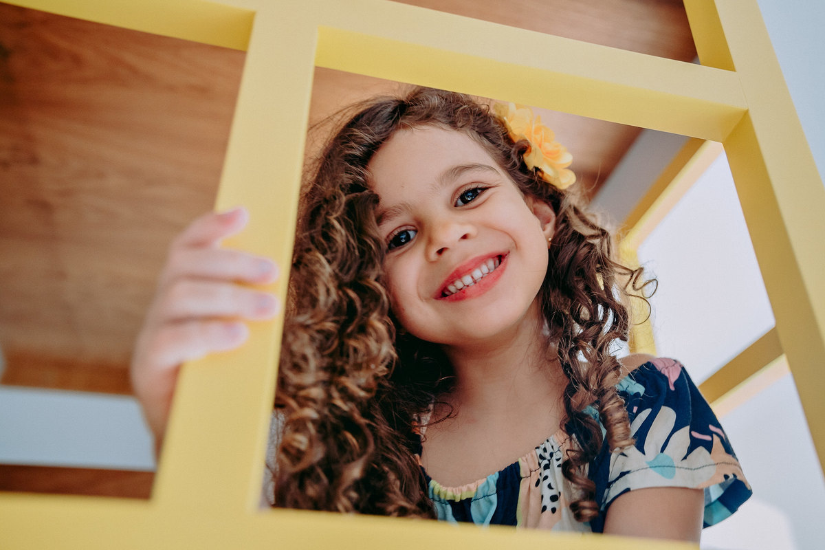 menina sorrindo em moldura amarela
