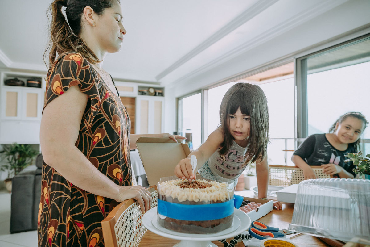 foto documental de mae com os olhos fechados aguardando a surpresa que a filga estava preparando e sendo observada por uma coleguinha