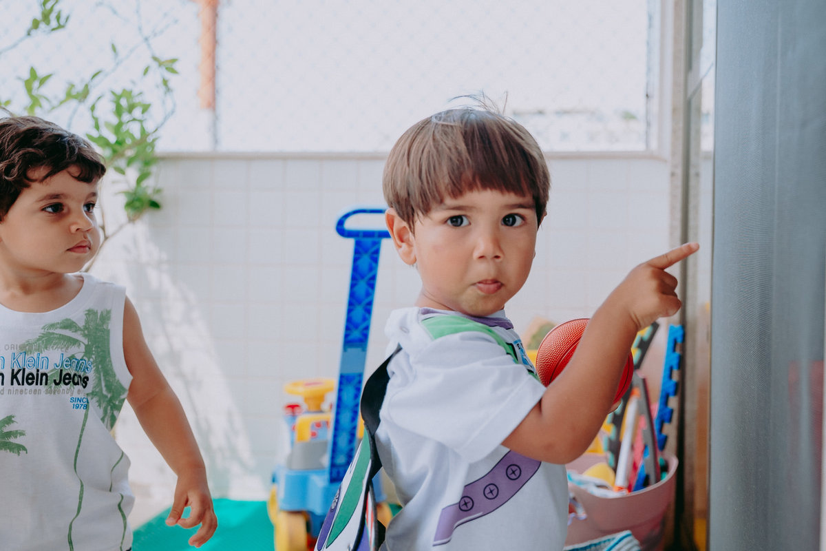 menino apontando pra um lugar e fazendo cara de surpreso