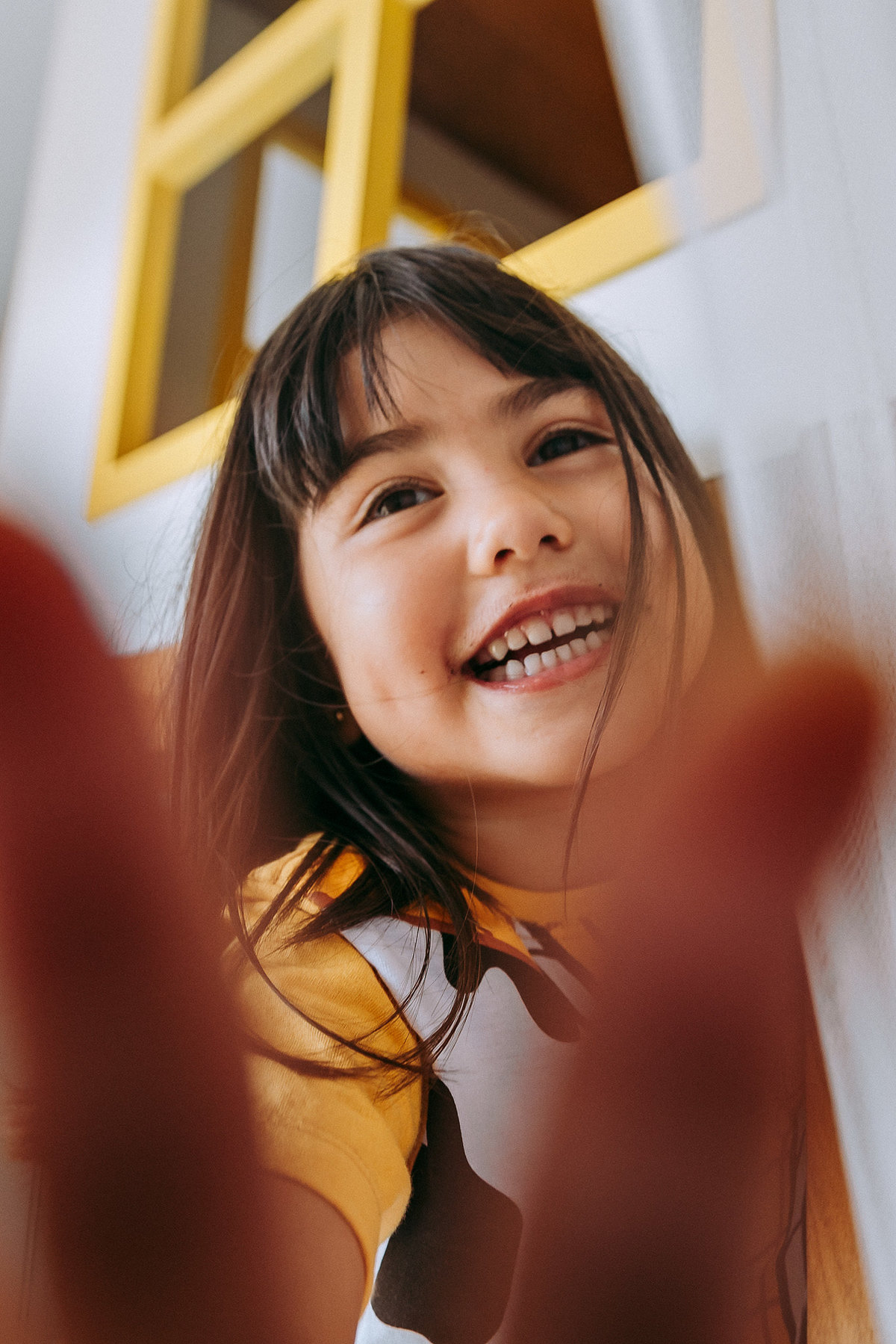 menina sorrindo colocando a mao na lente da camera