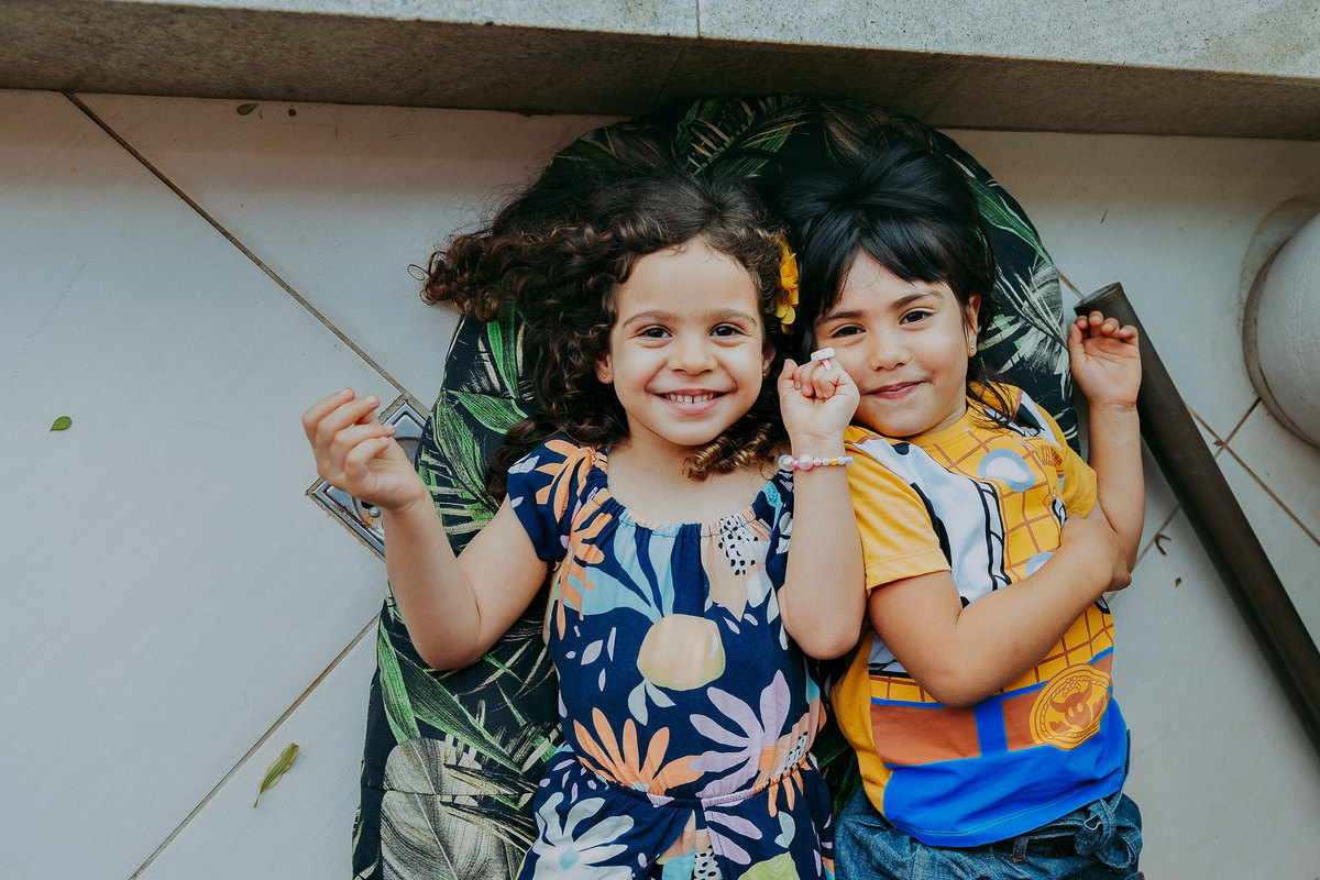 duas meninas deitadas no chão sorrindo pra foto