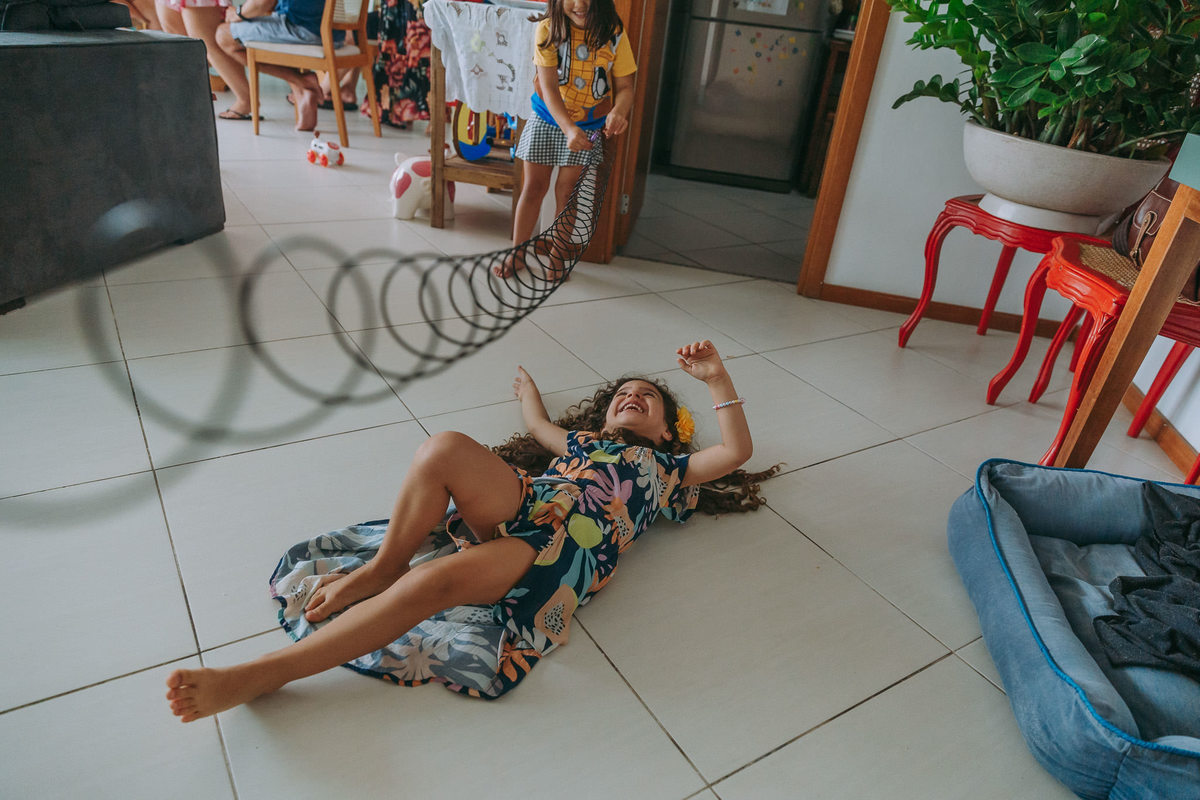 duas meninas brincam de pular corda com mola maluca e uma deitada no chao