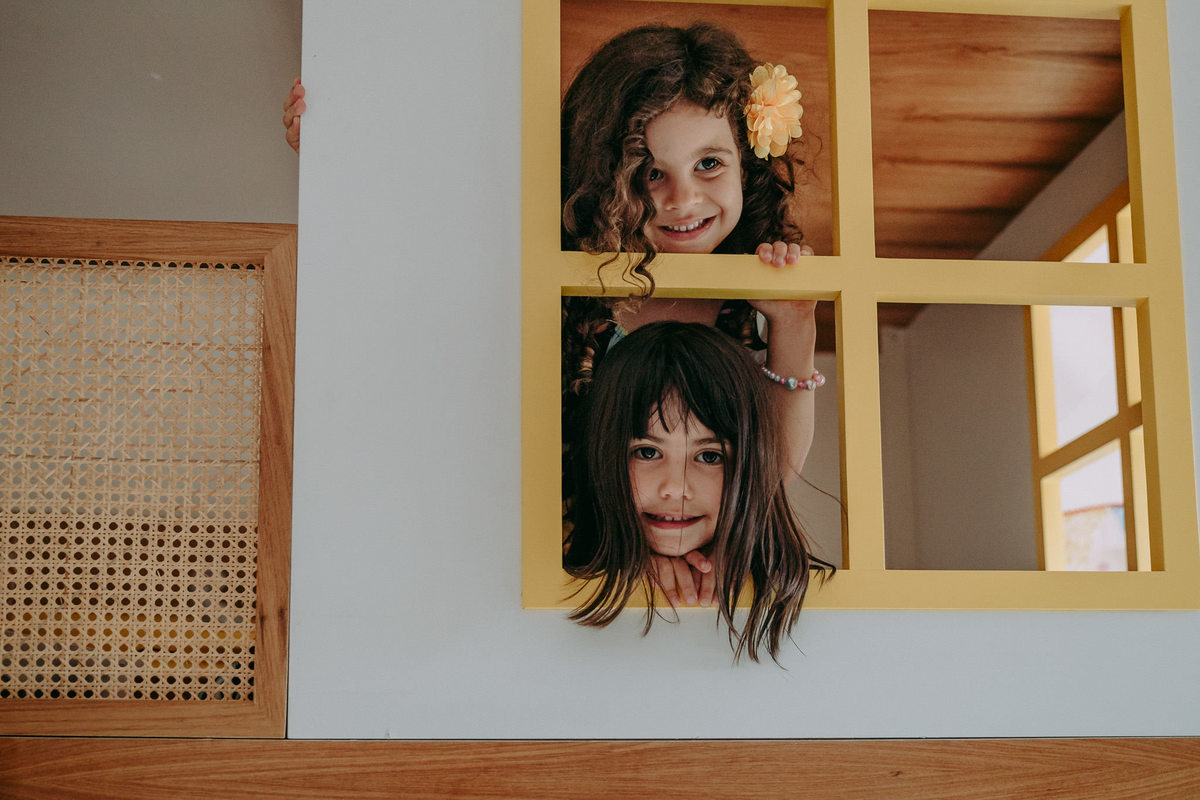 duas meninas em vão de janela amarela da cama do quarto