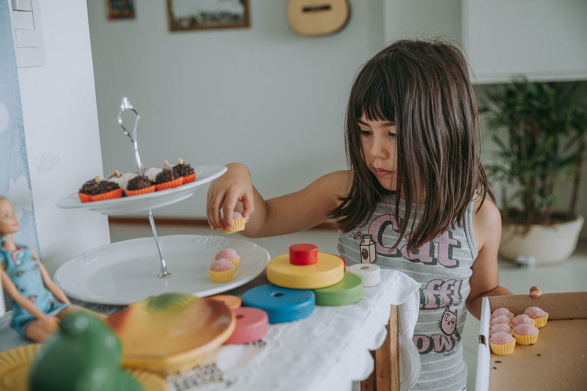 fotografia documental de criança arrumando os docinhos da mesa da festa de aniversario de seu irmao no Recreio dos Bandeirantes