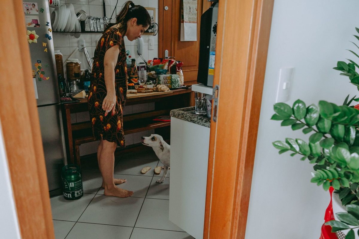 foto documental de mulher dando bonca em cachorro por ter derrubado os paes no chão