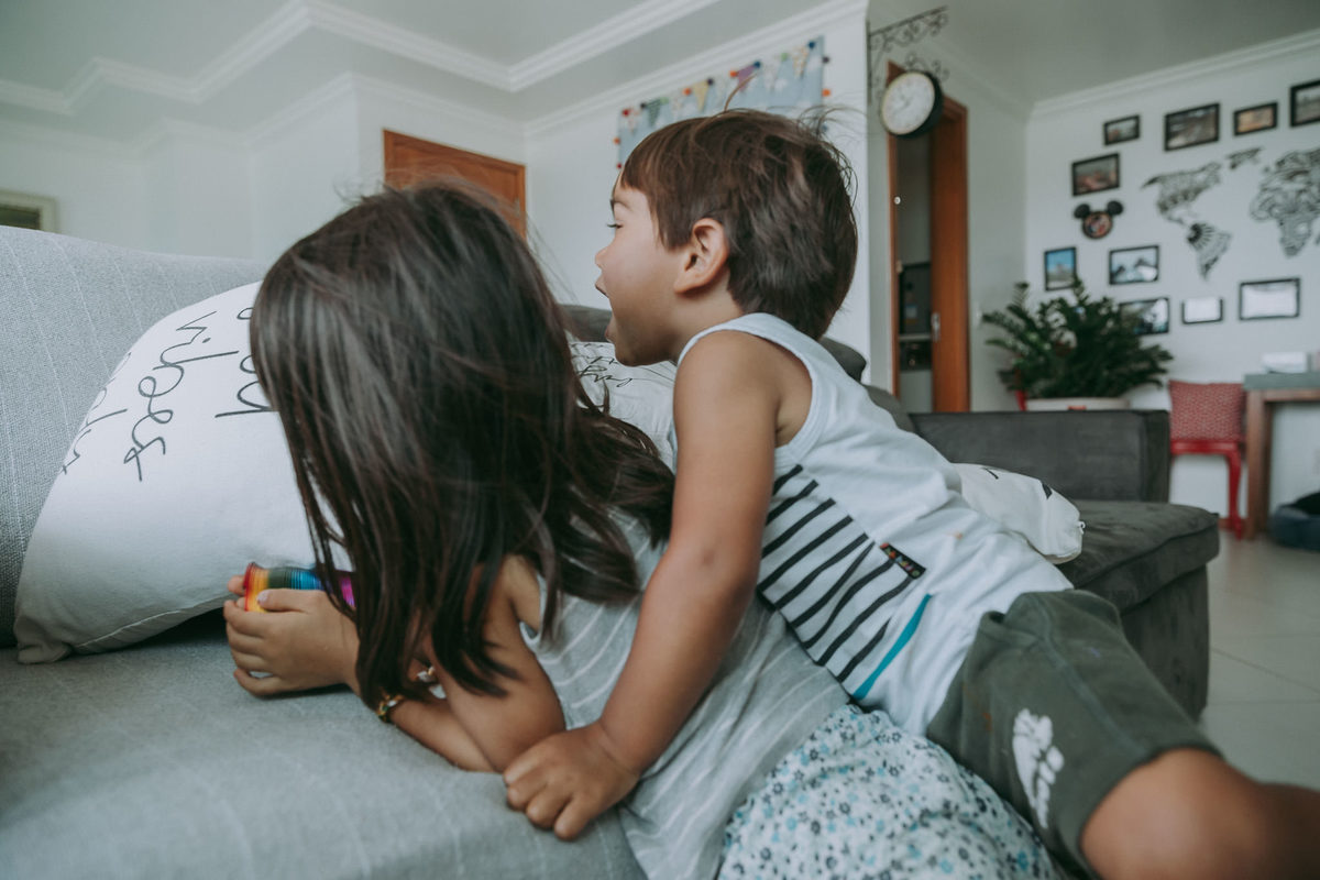 foto documental de irmãos fazendo bagunça na sala de casa