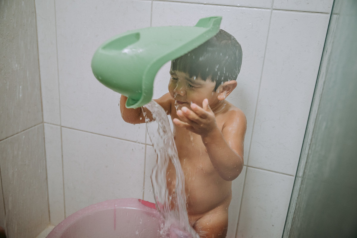 foto documental de menino de 2 anos brincando durante o seu banho