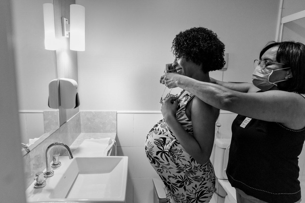 mãe ajudando a filha gestante a se trocar no banheiro para por a roupa do hospital