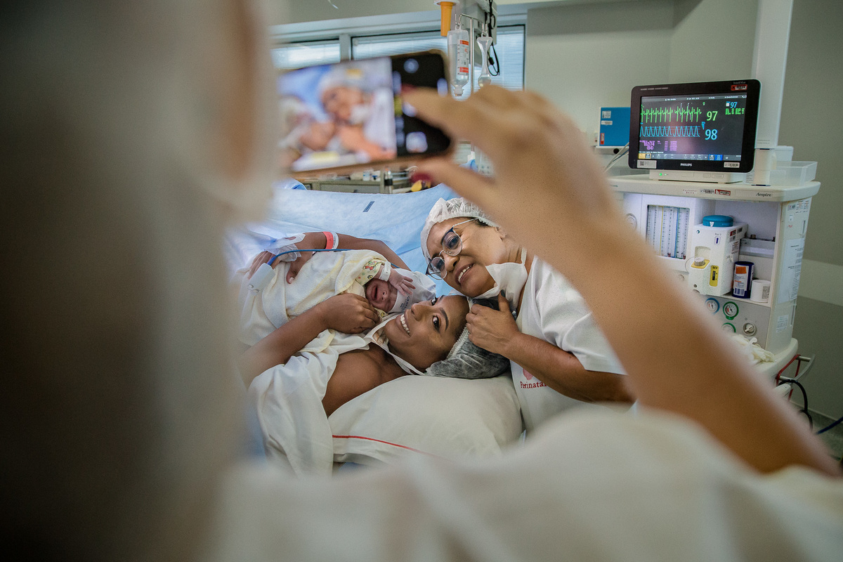 pediatra fotografa com celular primeiro encontro de mae com seu filho e avó materna após cesária na perinatal da barra da tijuca