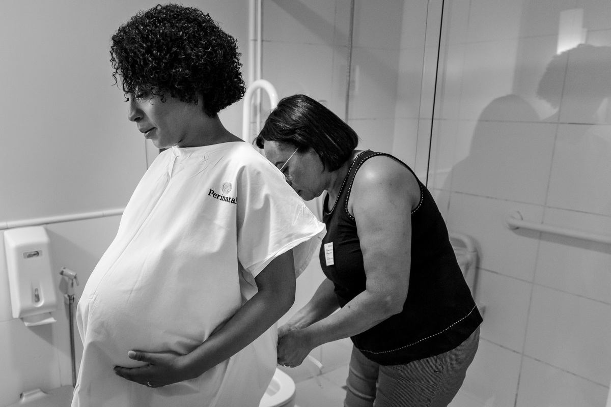 foto em preto e branco de mae de gestante ajudando a ela a se trocar para seguir para a cesária