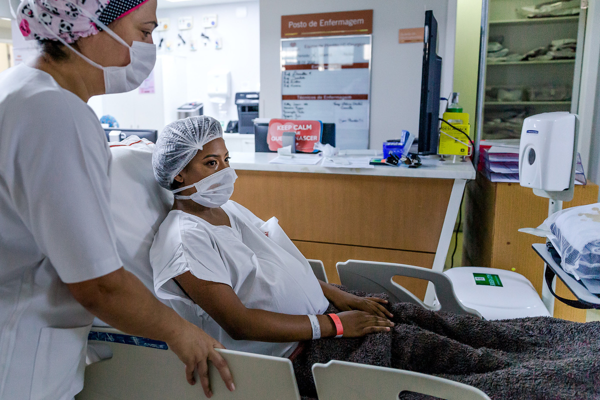 gestante de mascara chora enquanto é levada por pediatar na maca para o centro cirurgico da perinatal