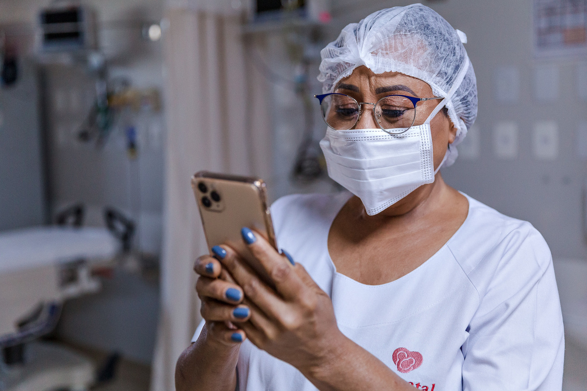 mae de mascara e segurando seu celular se emociona ao ver sua filha seguir para centro cirurgico