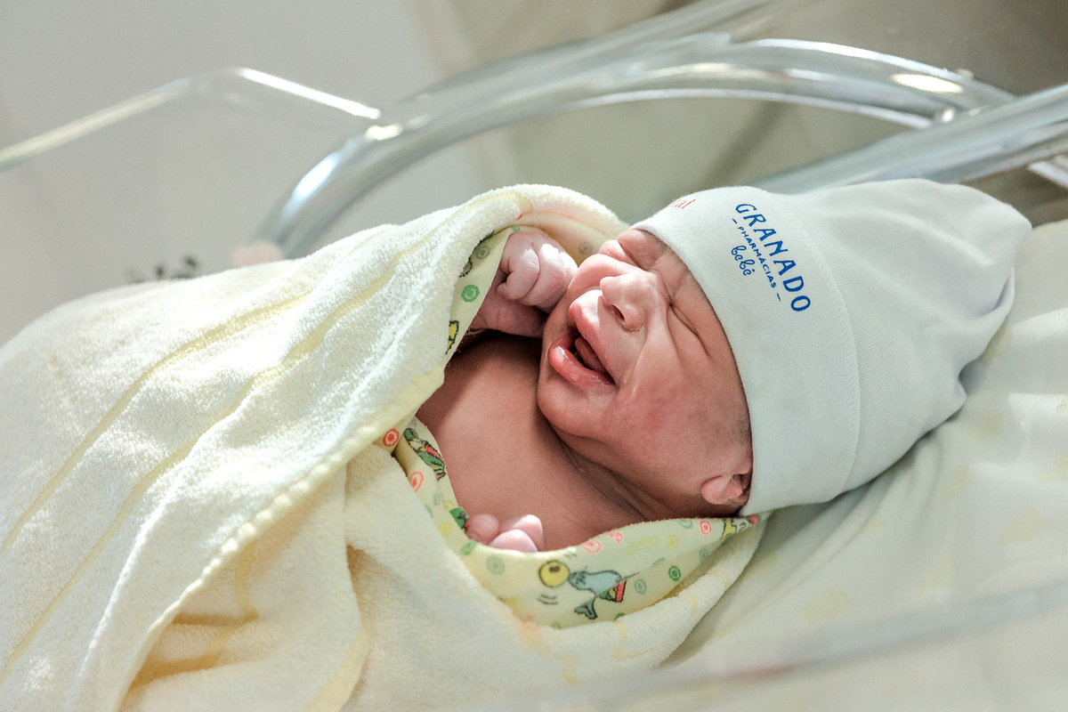 bebê envolto em manta amarela e touquinha da granado no berçario da perinatal da barra