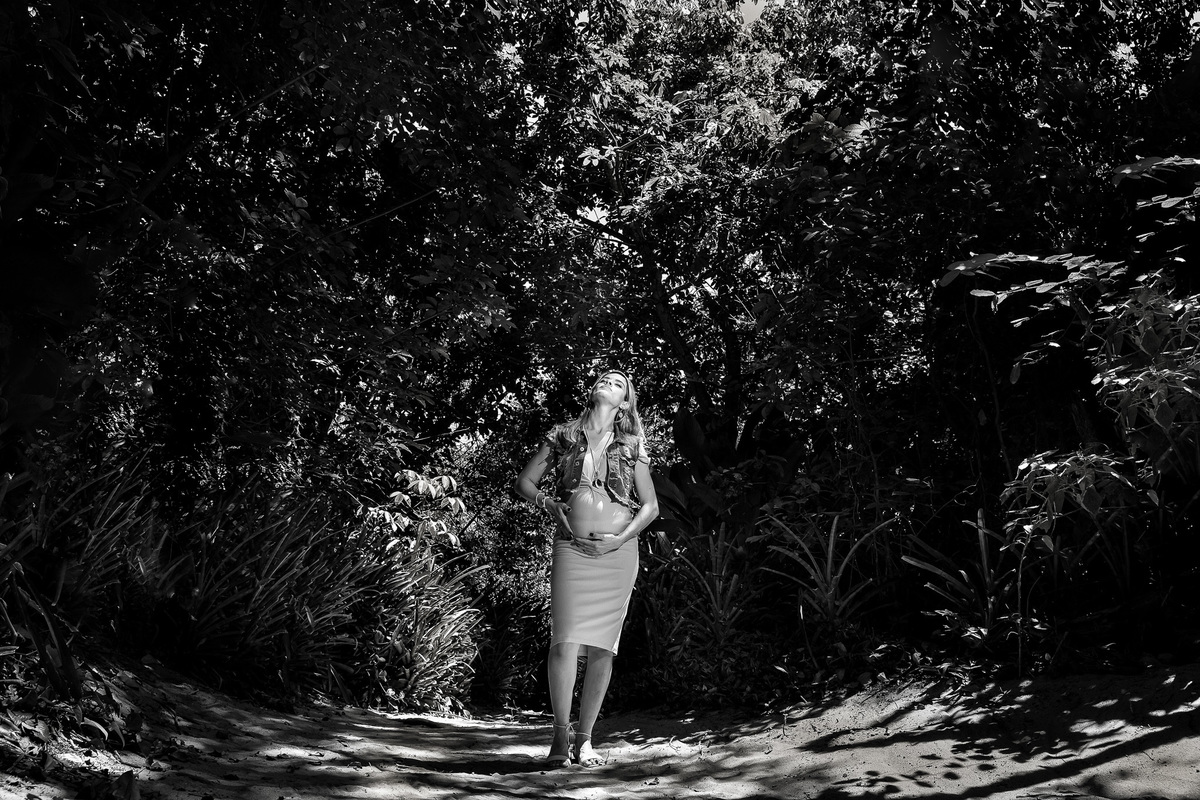 foto em preto e branco de gestante olhando para o alto e com um feixe de sol sobre ela 