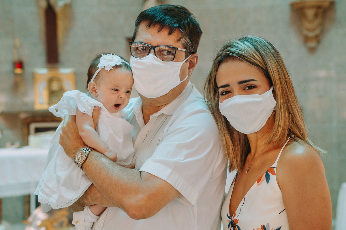 padrinhos em frente ao altar segurando sua afilhada bebê no colo e esta boceja na Paróquia São Marcelino de Champagnat