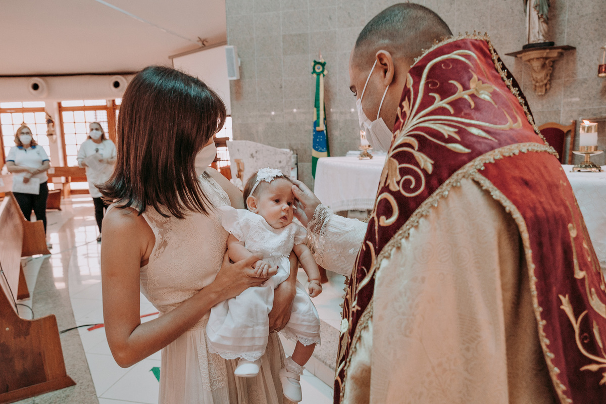 padre abençoa menina que está no solo de sua mae em seu batismo na Paróquia São Marcelino de Champagnat