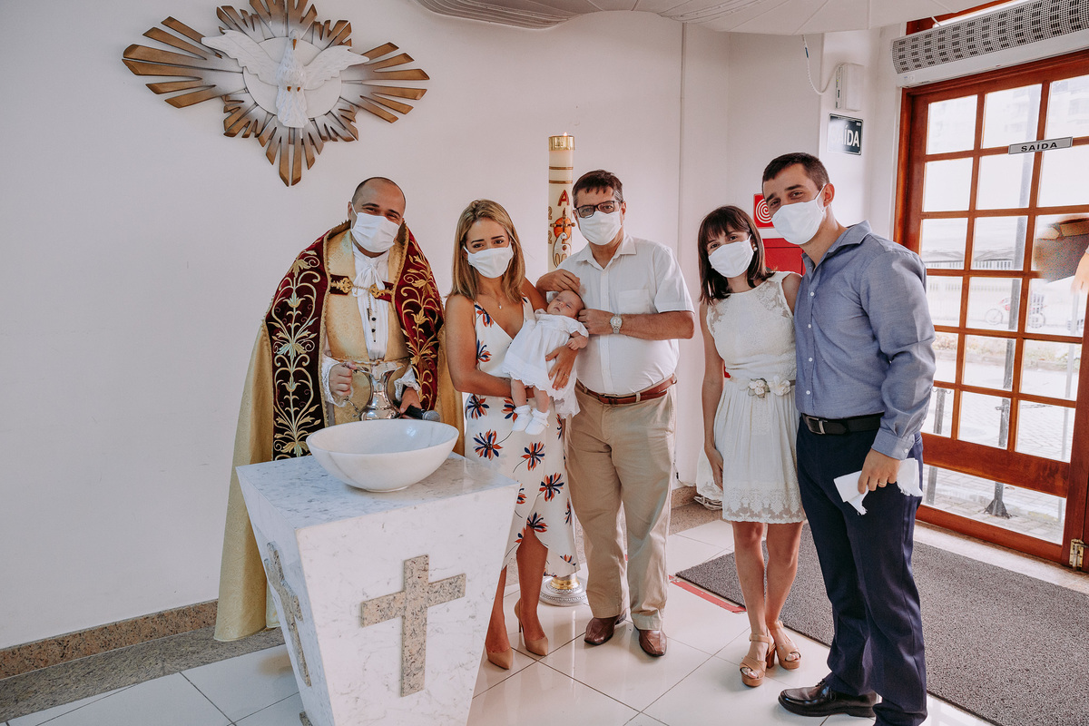 padrinhos pais e padre posam na pia batismal junto da criança batizada na Paróquia São Marcelino de Champagnat