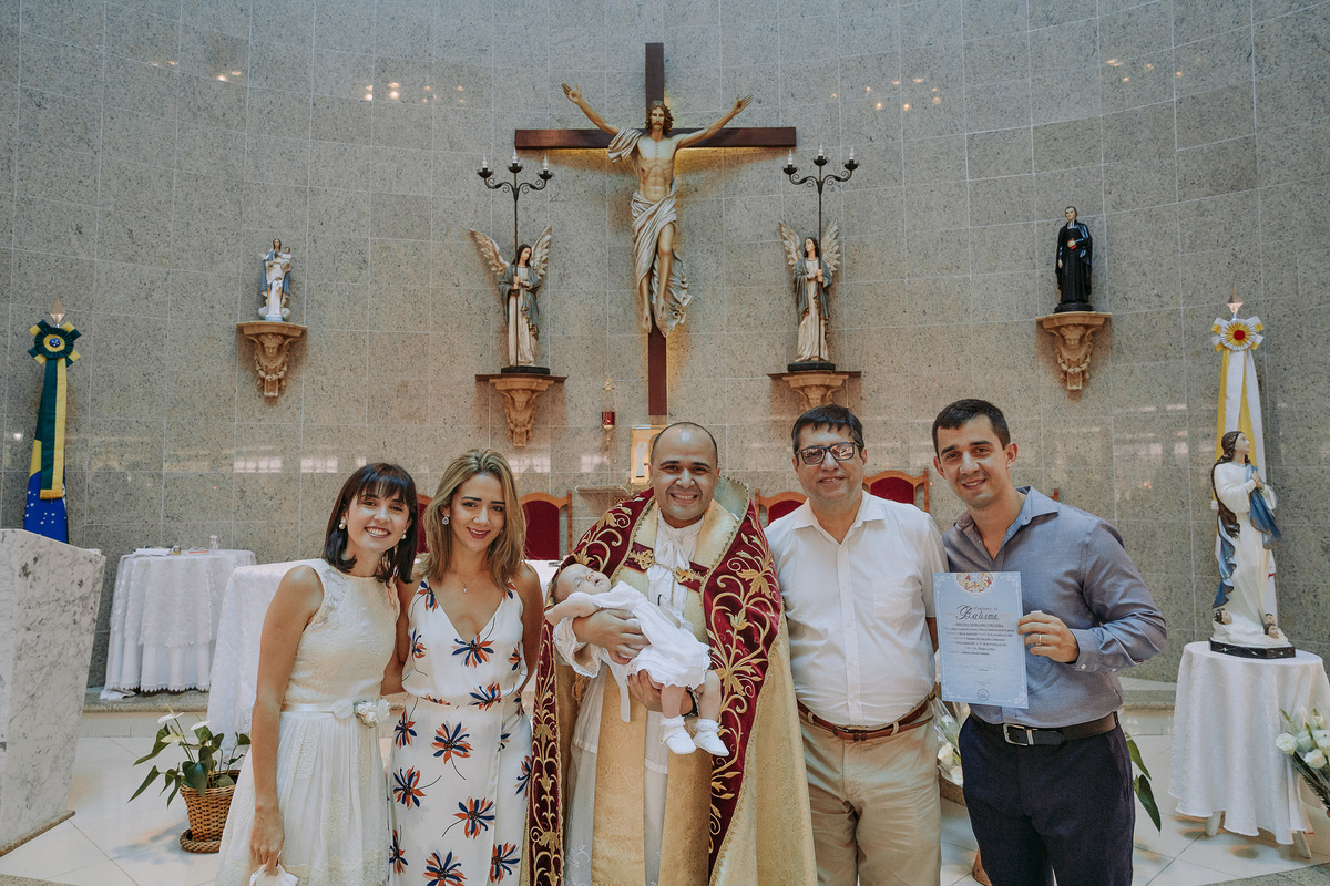 padrinhos, pais e padre posando para a foto junto da beb~e heloisa em seu batismo na Paróquia São Marcelino de Champagnat