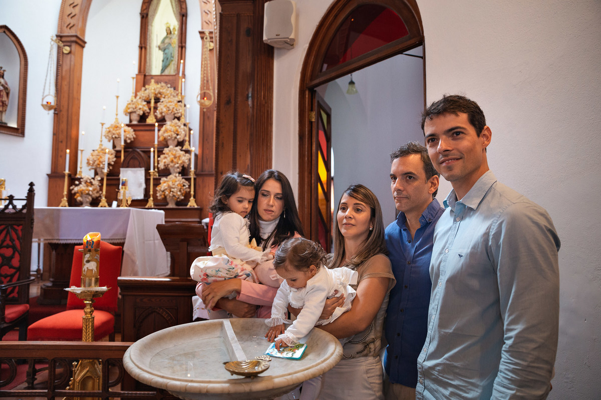 criança binca em pia batismal rodeada de familiares na paroquia nossa senhora da luz