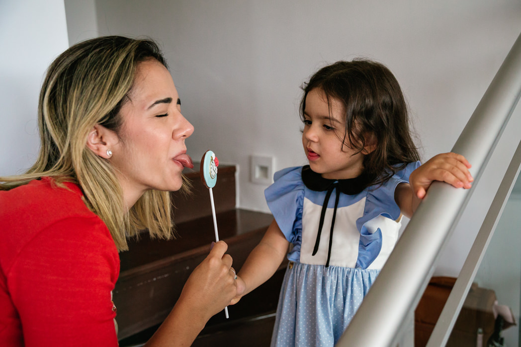 mae lambe pirulito de chocolate de olhos fechados brincando com sua filha que a observa