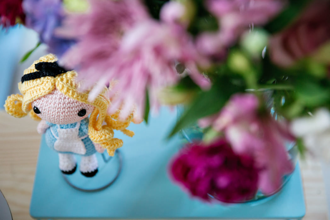 foto de aumigurumi de alice no pais das maravilhas e um arranjo de flores