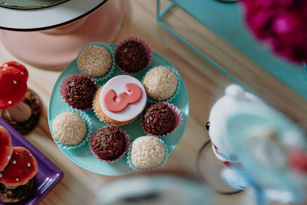prato de docinhos com brigadeiros e docinhos de coco e no meio um cupcake com o numero tres na cor rosa