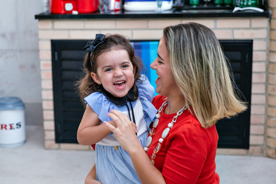 filha gargalha no colo de sua mae