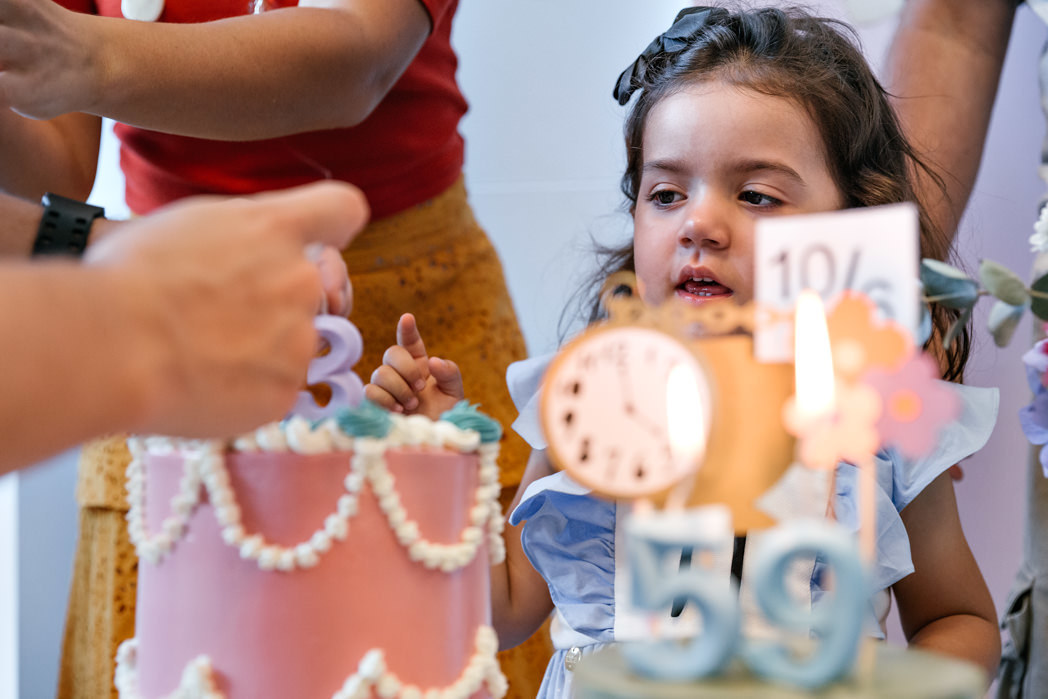 menina acompanha o acender das velas de seu bolo de aniversario de 3 anos na barra da tijuca