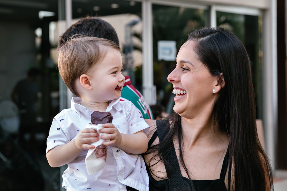 menino lambuzado com picole de açai sorri pra mae