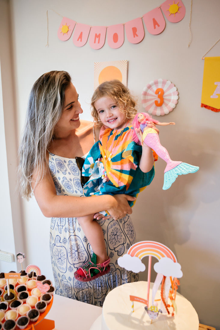 menina de 3 anos serura boneca de sereia no coloca mãe atras da sua mesa de bolo sunshine