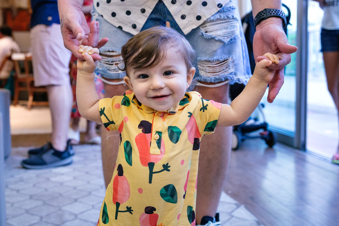 criança com roupa da farm sendo segura pelos dedos e aprendendo a andar