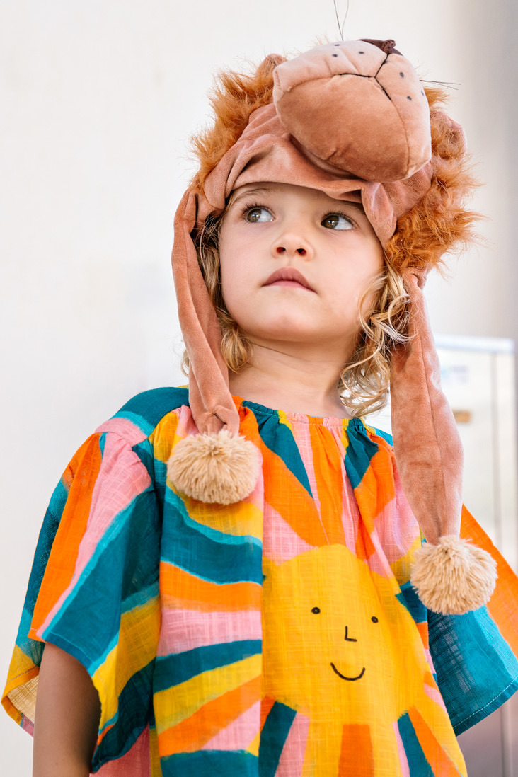 menina fantasiada de leao olhando para o lado esquerdo da foto em contra plonge