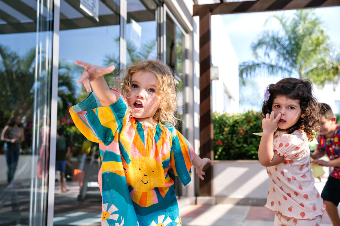 duas meninas uma loira arremessa uma gaivota e faz uma cara de força e a outra observa com dedo do nariz