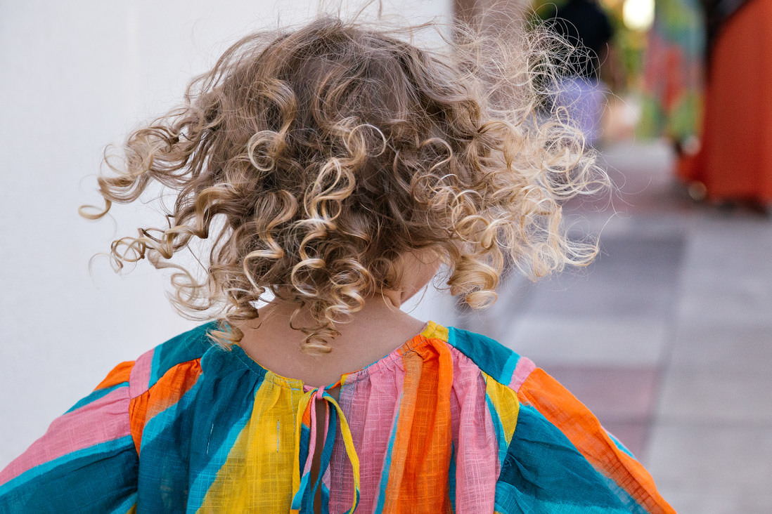 menina de cabelos cacheados e dourados de costa