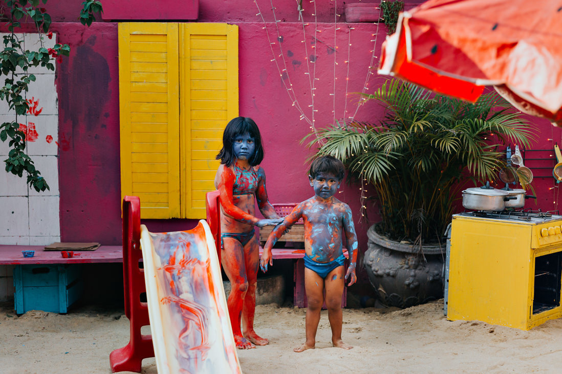 em casa de festas, irmao cobertos de tinta vermelha e azul olham apara a camera