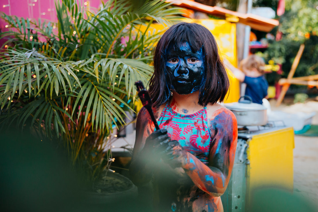 foto horizontal menina com rostos com tinta preta e cabelos lisos encara a camera