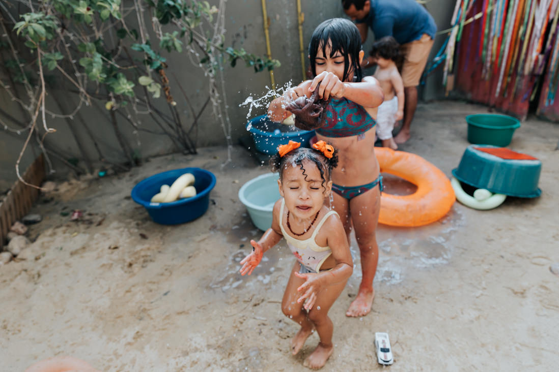 menina joga agua na cabeça da outra