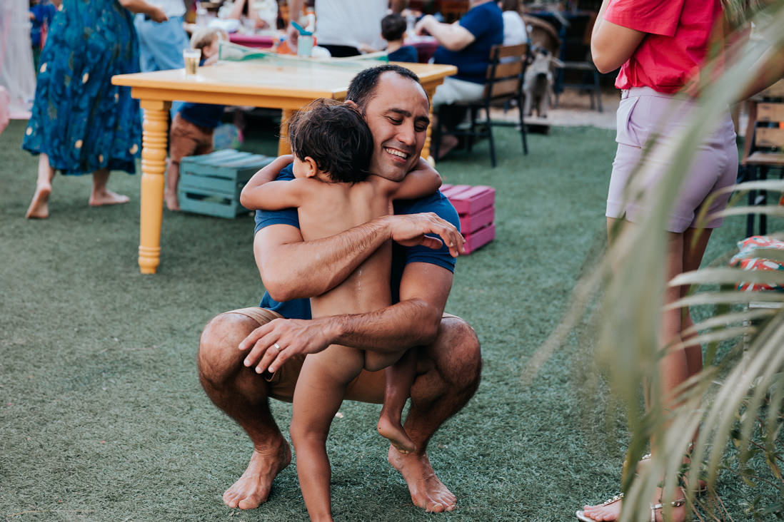 pai e filho agachados no chao abracados