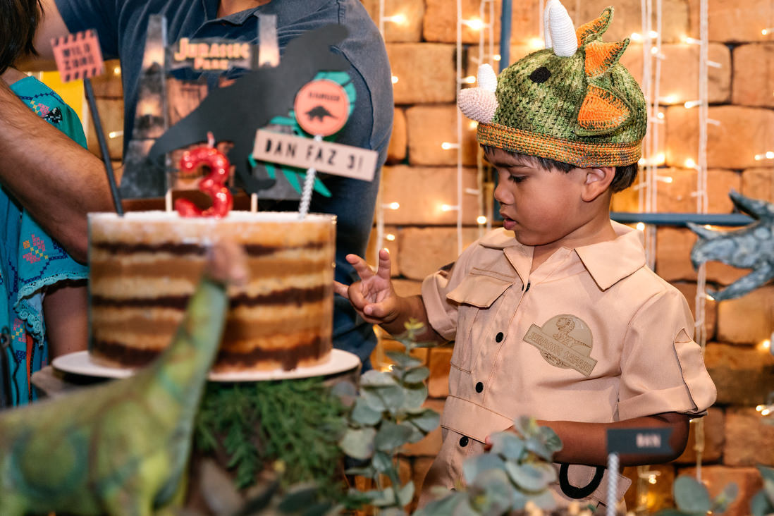 menino concentrado tenta fazer o numero 3 com os dedinhso no dia do seu aniversario