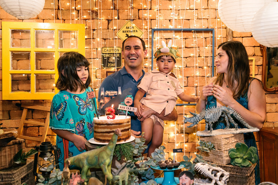 pai sorri com filho, filha e esposa na mesa no bolo