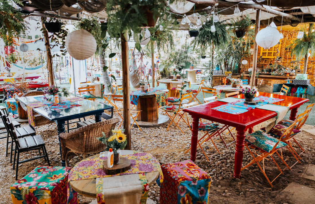 espaço com mesas e cadeiras em frente a mesa do bolo da casa de festas O quintal no Recreio dos Bandeirantes