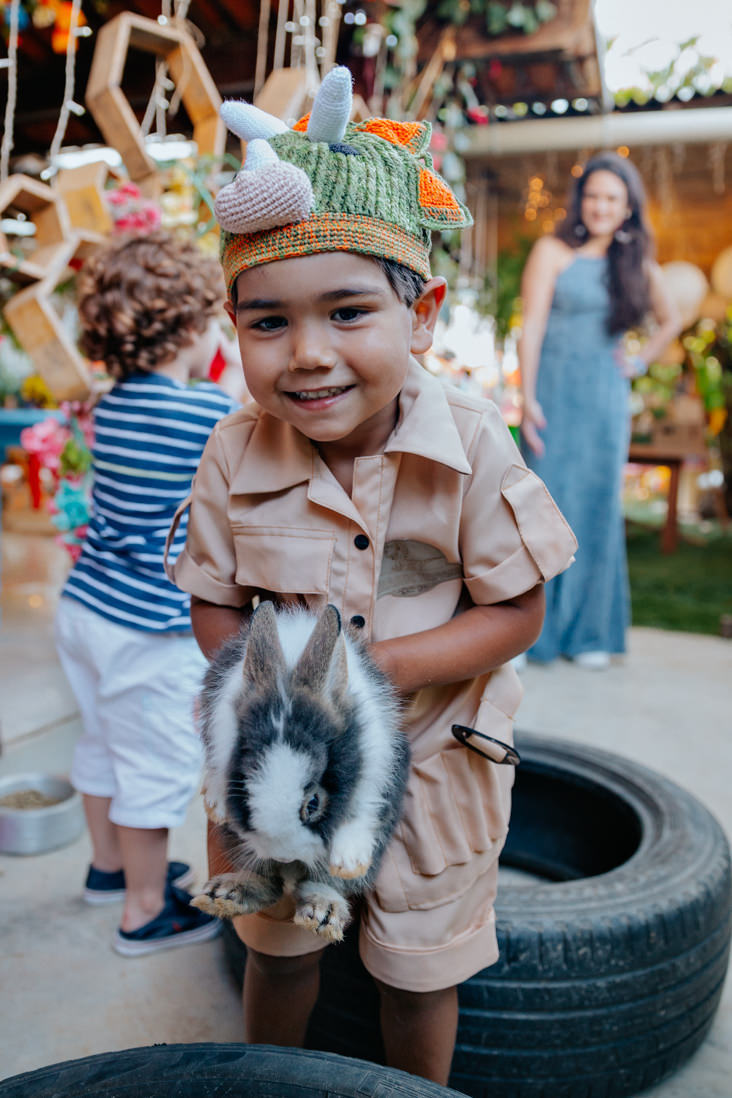menino de 3 anos fantasiado segura coelho em suas maos