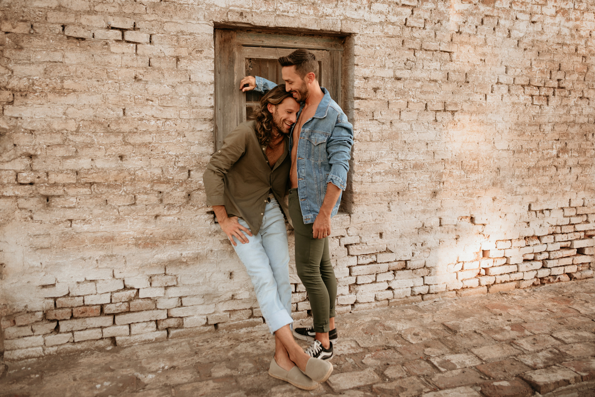 Pareja de hombres. Amor. Conexión. Modelos masculinos. Pareja sobre ventana.