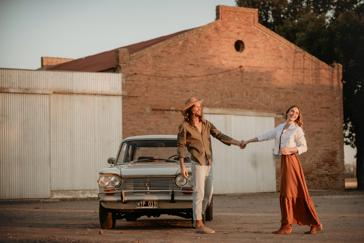 Atardecer con pareja apoyada en auto de colección. Pareja modelo. Amor.