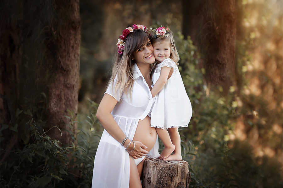 Disfrutando en el campo una hermosa tarde de verano, esperando con ansias la llegado de su hermanito. Vestidos blancos con coronas de flores en el bosque. Barby Massei Fotógrafa. Sesión maternidad.