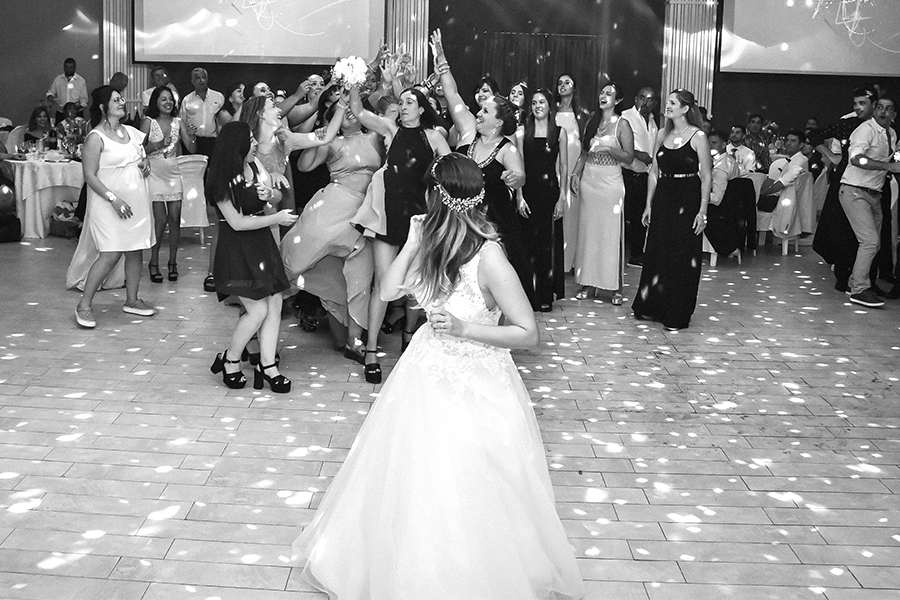 Novia tirando el ramo de rosas blancas en su fiesta de casamiento. Pista de baile divertida en San José de la Esquina. Fotografía blanco y negro Barby Massei.